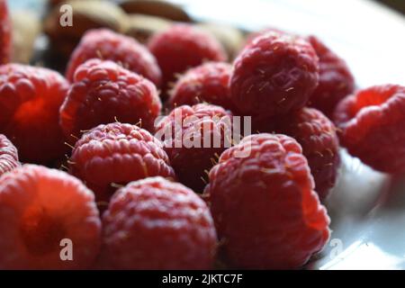 A close up of fresh raspberries placed on a white plate Stock Photo