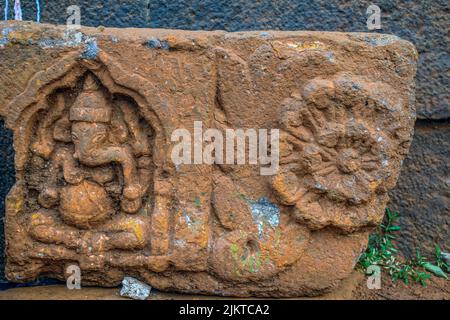 Stock photo of Ancient ruined archeological sculpture of hindu god ganesha engraved on gray stone wall. Picture captured during sunny day at Kolhapur Stock Photo