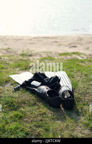 Vertical shot of a snorkeling set on a beach, diving fins, swim trunks, diving mask and snorkel. Water sports equipment. Stock Photo