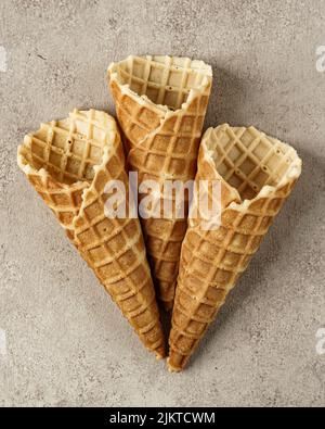 A vertical shot of three empty ice cream cones over brown background Stock Photo