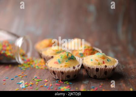 A closeup of cupcakes decorated with colorful candies on a wooden table Stock Photo