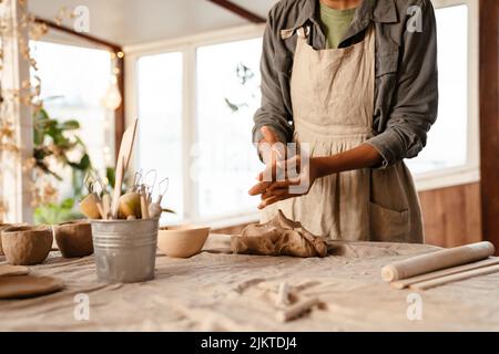 Young black ceramist woman wearing apron sculpting in clay at her workshop Stock Photo