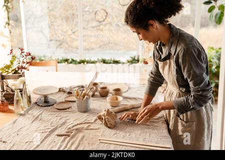 Young black ceramist woman wearing apron sculpting in clay at her workshop Stock Photo