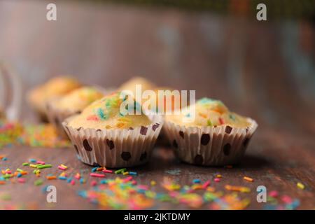 A closeup of cupcakes decorated with colorful candies on a wooden table Stock Photo