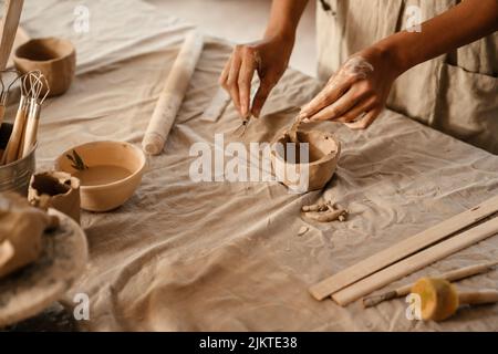 Young black ceramist woman wearing apron sculpting in clay at her workshop Stock Photo