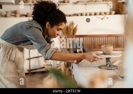 Young black ceramist woman wearing apron sculpting in clay at her workshop Stock Photo