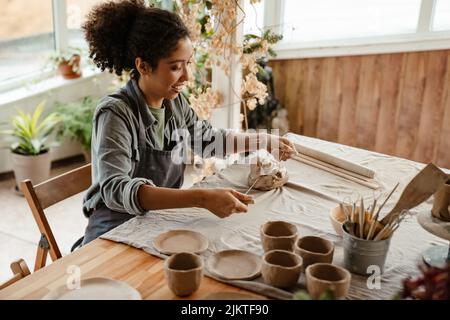 Young black ceramist woman wearing apron sculpting in clay at her workshop Stock Photo