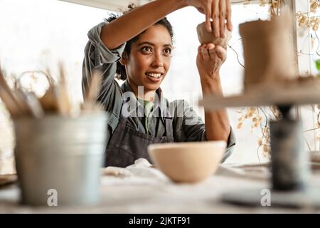 Young black ceramist woman wearing apron sculpting in clay at her workshop Stock Photo