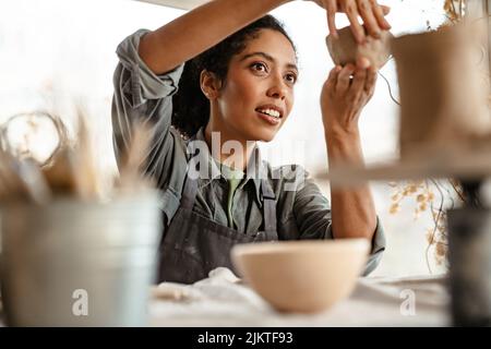 Young black ceramist woman wearing apron sculpting in clay at her workshop Stock Photo