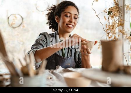 Young black ceramist woman wearing apron sculpting in clay at her workshop Stock Photo