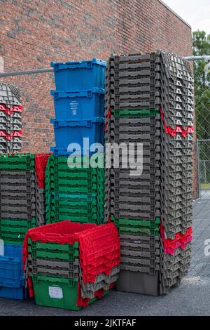 Augusta, Ga USA - 05 21 21: Stacks of empty colorful totes behind a retail store Stock Photo