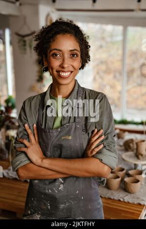 Young black ceramist woman wearing apron smiling while working in her ...