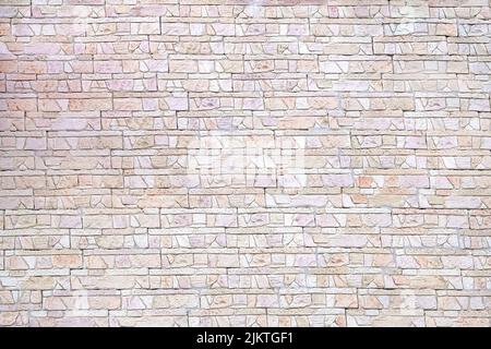 Wall covered with decorative tiles in the form of pieces of bricks. The texture of the old brickwork. Selective focus. Close-up. Copy space. Stock Photo