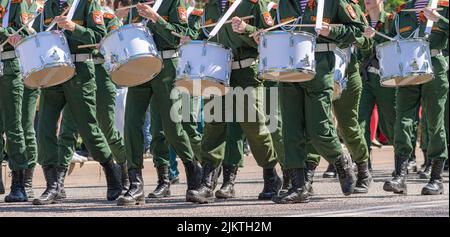 Group of young drummers, dressed in camouflaged military uniforms, marches down city street and plays drums. May 9 is annual victory day holiday. Stock Photo