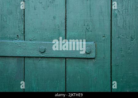 Vertical wooden planks with the horizontal metal element are covered in green paint. Close-up view. Wooden vintage background. Stock Photo
