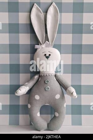 Easter bunny textile toy by handmade on checkered. Decorative soft toy, DIY Stock Photo