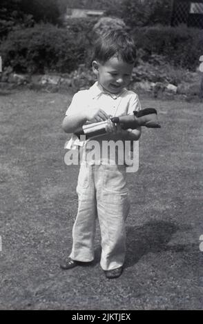 1967, historical, outside in garden, a happy little boy standing on the grass holding his soft toy, a golly, England, UK. Stock Photo