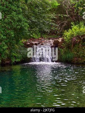 A vertical shot of a small waterfall merging into the Paiva river in the Arouca Geopark on a sunny day Stock Photo