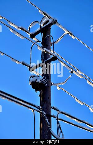 A vertical shot of power line covered by snow Stock Photo