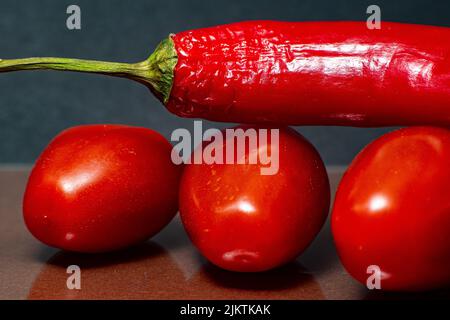A closeup of three tomatoes and a red pepper on the top Stock Photo