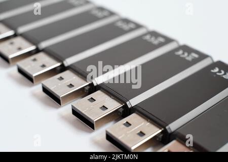 Many black USB sticks in a row with white background. Production of flash drives for data storage. Stock Photo
