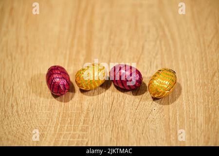 A closeup of pink and yellow Easter egg chocolate candies on a wooden surface Stock Photo