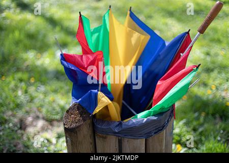 A closeup of a broken multicolor umbrella thrown in a trash can. Stock Photo