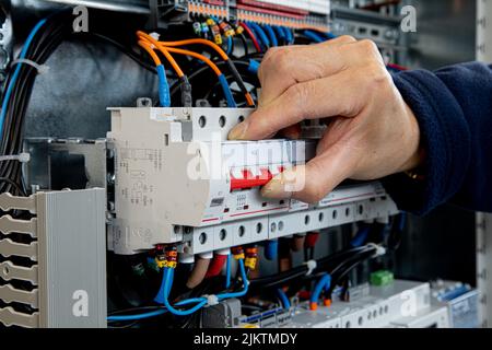 A closeup of the hand switching on a circuit breaker to power an electrical installation. Stock Photo