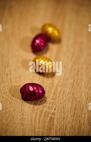 A vertical shot of colorful wrapped chocolate Easter eggs set on a table Stock Photo