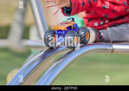 A child playing with a hot wheels monster truck in the playground Stock Photo