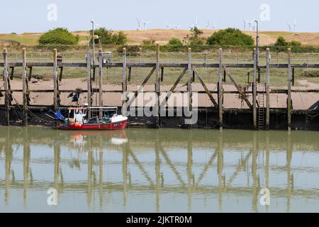 Red fishing boat in Rye Harbour at low tide - Rye, West Sussex, England, UK Stock Photo