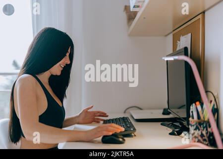 A young Hispanic woman sitting against a computer and looking at the came Stock Photo