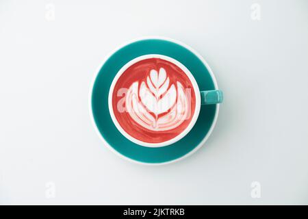 A top view of pink-colored cappuccino with a feather drawing, in a blue cup, over a white background Stock Photo