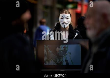 A female activist wearing an Anonymous mask on the streets of Great Britain Stock Photo