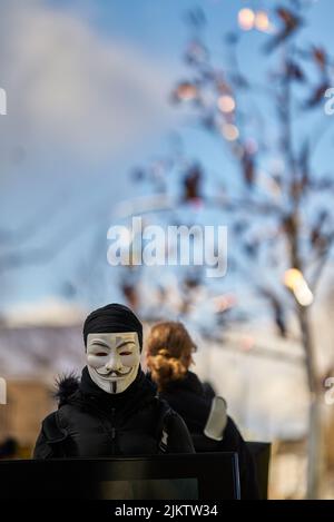 A female activist wearing an Anonymous mask on the streets of Great Britain Stock Photo