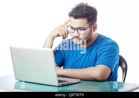 young student thinking in front of a laptop looking at laptop screen Stock Photo