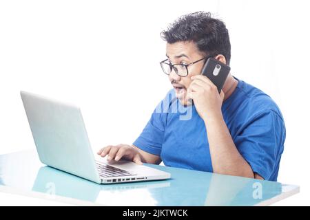 shocking man reading message on computer screen and talking over phone Stock Photo