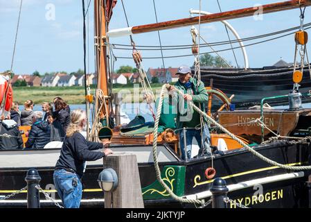 Crew mooring up Hydrogen, historic Thames sailing Barge, at Maldon Hythe Quay on the River Blackwater, Maldon, Essex, UK. Passing rope to quayside Stock Photo