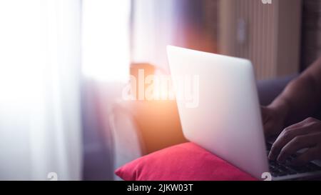 young man at home using his computer and phone having cup of coffee Stock Photo