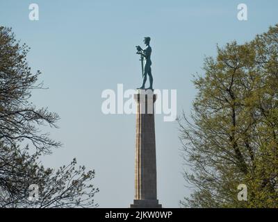 The tall Pobednik monument in Belgrade Fortress from the frame of the trees in Serbia Stock Photo