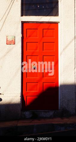A beautiful shot of a red wooden door on a traditional house in bright sunlight in Valparaiso, Chile Stock Photo