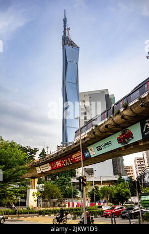 A vertical shot of the world's second-tallest building Warisan Merdeka Tower with the train running on the foreground Stock Photo