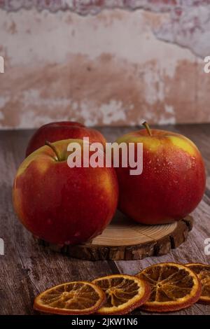 close-up of three fresh red apples with drops of water on a slice of wood Stock Photo