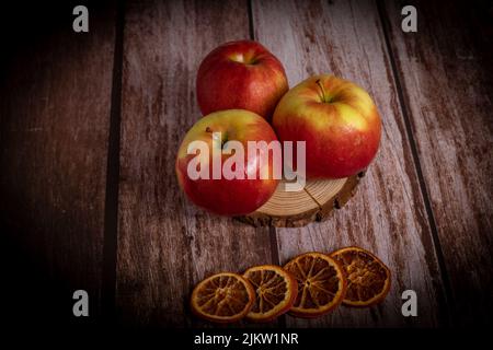 close-up of three fresh red apples with drops of water on a slice of wood Stock Photo