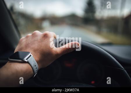 a human hand holding steering wheel and wearing smart watch. Stock Photo