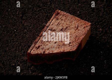 A closeup shot of a broken brick on an asphalt ground Stock Photo