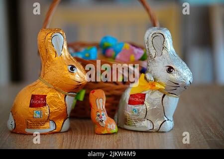 The Favorina brand small Easter chocolate bunnies packed in foil standing in front of a basket Stock Photo