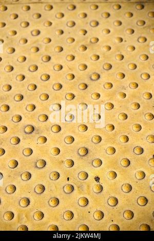 A vertical shot of a metal yellow background with knobs Stock Photo