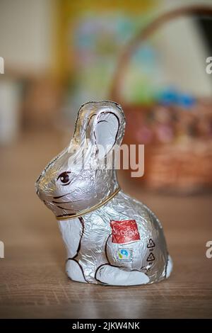 The Favorina brand Easter chocolate bunny packed in silver foil standing on a wooden table Stock Photo