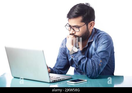 young handsome person thinking and planning by looking at laptop screen in white background Stock Photo